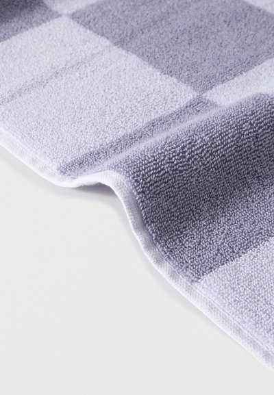 Μαλακή πετσέτα από περκάλι με καρό μοτίβο σε ανοιχτό και σκουρό γκρι, μερικώς διπλωμένη πάνω σε λευκή επιφάνεια.