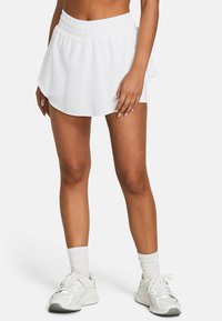 White athletic skirt with an elastic waistband, flared design, and smooth fabric. Worn with white sneakers and crew socks.