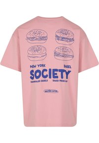 Pink cotton t-shirt featuring four bagel illustrations and bold blue text reading "NEW YORK BAGEL SOCIETY" on the back.
