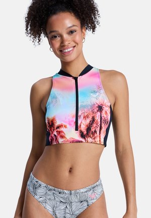 Kleurrijke roze en blauwe crop top met een ritssluiting aan de voorkant, met een palmboomdesign. Gecombineerd met zwart-wit gestreepte bikinibroekjes.