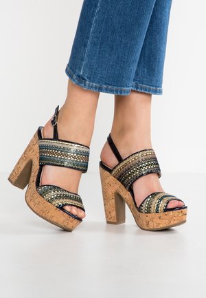 Blockabsatzsandalen mit Korkbasis, ausgestattet mit metallischen Riemen in Marineblau, Gold und Teal. Offene Zehen-Design mit Knöchelriemen und Schnallenverschluss.