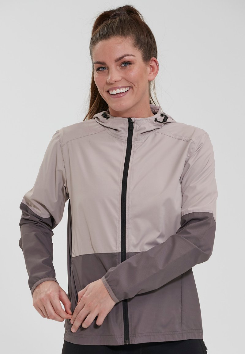 Let light, beige og grå vindjakke med lynlås lukning, justerbar hætte og lommer; har farveblokket design og glat tekstur.