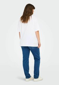 Balta didelė t-shirt su trumpomis rankovėmis, derinama su mėlynomis džinsomis. Aprangą papildo baltos sportbačiai. Paprastas ir kasdieniškas dizainas.