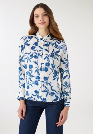Koszula na guziki z białej tkaniny z nadrukiem niebieskich kwiatów i liści. Posiada długie rękawy i kołnierzyk, gładka faktura.