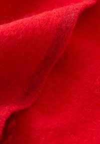 Red wool fabric showcasing a soft, fluffy texture with subtle variations in shade. The material appears thick and cozy, with a smooth drape.