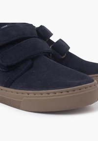 Granatowe zamszowe buty z dwoma rzepami, beżowa gumowa podeszwa, zaokrąglony czubek i kontrastujące przeszycia. Idealne na co dzień.