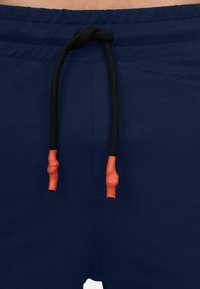 Marineblauwe shorts met een gladde textuur, voorzien van een zwarte trekkoord met oranje uiteinden en een elastische tailleband voor een veilige pasvorm.
