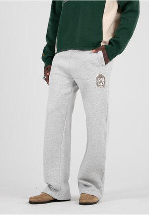 Pantalones de chándal de algodón gris claro con un corte relajado, que presentan un emblema bordado en la parte superior de la pierna y bolsillos laterales.