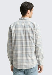 Geruite shirt in lichte kleuren met blauwe en grijze patronen. Knop-down kraag met een enkele rugknop. Lange mouwen met knopfouds.