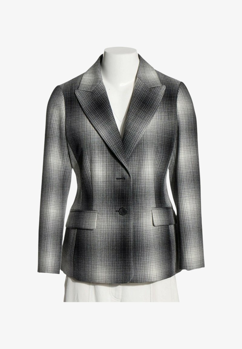 Blazer à carreaux gris et noir avec revers crantés, deux poches avant à rabat et une fermeture à un bouton sur un torse de mannequin blanc.