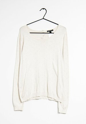 Pull léger blanc à manches longues avec motif à pois texturé, encolure ronde et poignets côtelés, suspendu à un cintre noir.