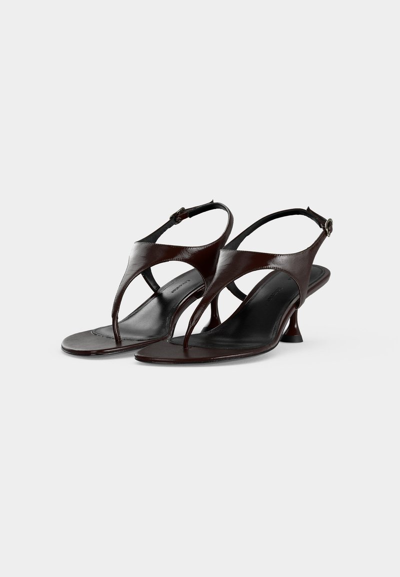 Donkerbruine leren slingbacksandalen met teenbandjes, kleine uitlopende hakken en verstelbare gespsluitingen op een witte achtergrond.