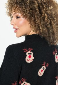 Schwarzer, gestrickter Pullover mit mehreren Rentiergesichtern, die rote Nasen und Geweih haben. Er zeichnet sich durch eine weiche Textur und eine figurbetonte Passform aus.