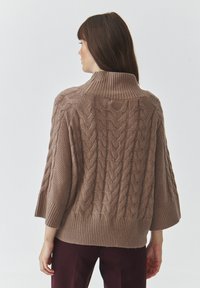 Brauner Kabelstrickpullover mit hohem Kragen, lockeren Ärmeln und geripptem Saum. Verfügt über strukturierte Muster und ein weiches, voluminöses Design.