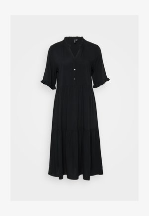 Rochie neagră, până la genunchi, cu un decolteu cu nasturi, mâneci scurte cu volane și un design stratificat. Realizată dintr-un material moale, având o textură subtilă.