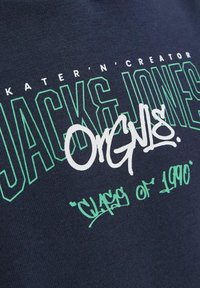 T-shirt en coton bleu marine avec un texte graphique blanc et vert comprenant "JACK & JONES" et "Class of 1990" avec une finition texturée.