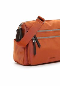Orange crossbody bag with two front zippered pockets, black zipper pulls, and an adjustable shoulder strap on a white background.