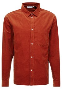 Camisa abotonada de color óxido, hecha de una tela suave, con un bolsillo en el pecho, mangas largas y botones blancos.