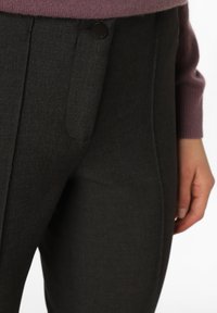 Pantaloni grigi scuri su misura con una finitura testurizzata, dotati di tasche laterali e un dettaglio in bottone nero in vita.