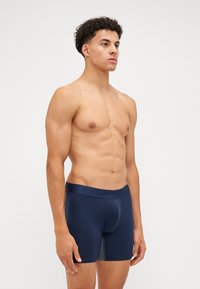 Dark navy boxer briefs made of smooth fabric, featuring a snug fit and an elastic waistband with embossed branding.