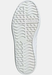 Suola di sneaker in gomma bianca con pattini testurizzati, caratterizzata da dettagli in rilievo e marchio al centro. Superficie liscia in tutto.