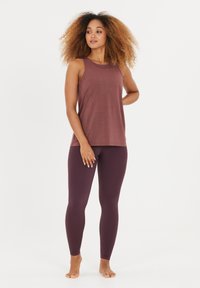 Top de tirantes marrón con un corte relajado, combinado con leggings de color burdeos oscuro. Tela suave, diseño sin mangas y estilo minimalista.