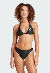 Svart bikinitopp med halterneck och triangulära kupor, samt matchande högmidjade trosor. Tillverkad av ett mjukt, lätt material.