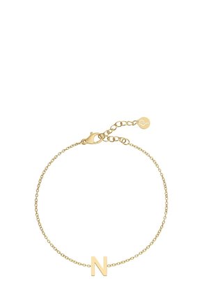 Auksinė grandinėlė su vienu raide "N" kaip pakabuku. Grandinėlė yra plona, turi spaudimo užsegimą ir reguliuojamą ilgį, kad būtų galima pritaikyti.