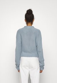 Ljusblå stickad cardigan med en kortad passform, långa ärmar och ribbad nederkant. Har en strukturerad design med lösa stygn.