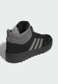 Zapatillas altas en negro y gris que presentan un upper de ante y sintético, un forro gris suave, tres bandas negras y una suela de goma texturizada.