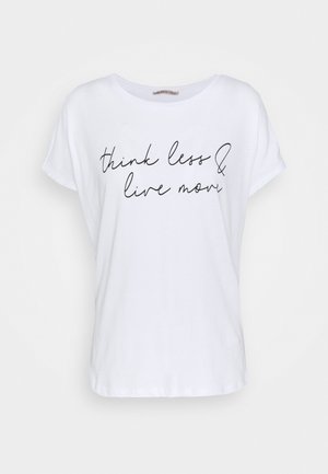 Camiseta blanca de manga corta con texto en cursiva negra que dice "piensa menos y vive más" en el frente, fondo liso.