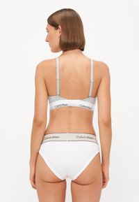 Grijze en witte bralette met verstelbare bandjes en logo op de band, gecombineerd met witte high-waisted slipjes met een contrasterende logo tailleband.