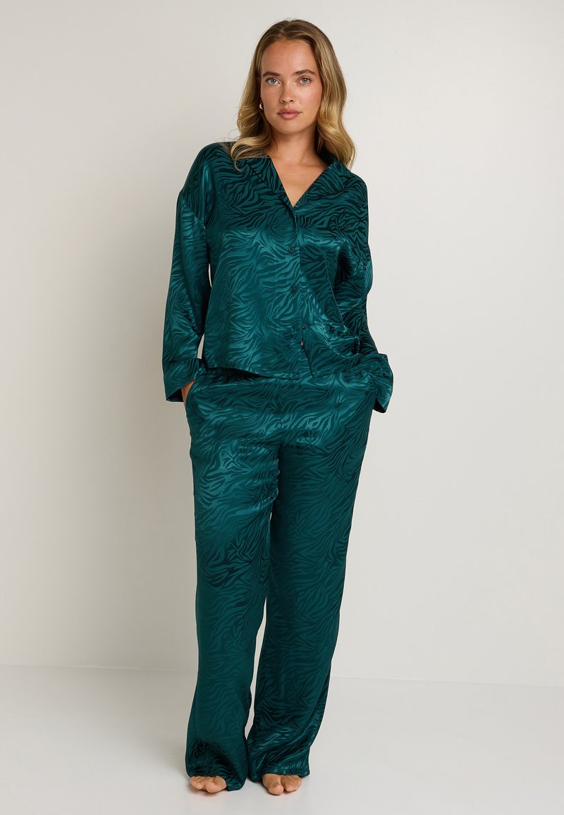 Ensemble de pyjama en satin teal avec un motif zèbre subtil, comprenant un haut à col et un pantalon à coupe décontractée, texture lisse et détails de boutons.