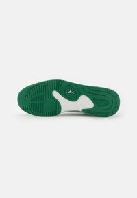 Semelle de sneaker blanche avec une semelle extérieure en caoutchouc vert, dotée de crampons texturés et d'un détail de logo au centre. Conçue avec une forme courbée.