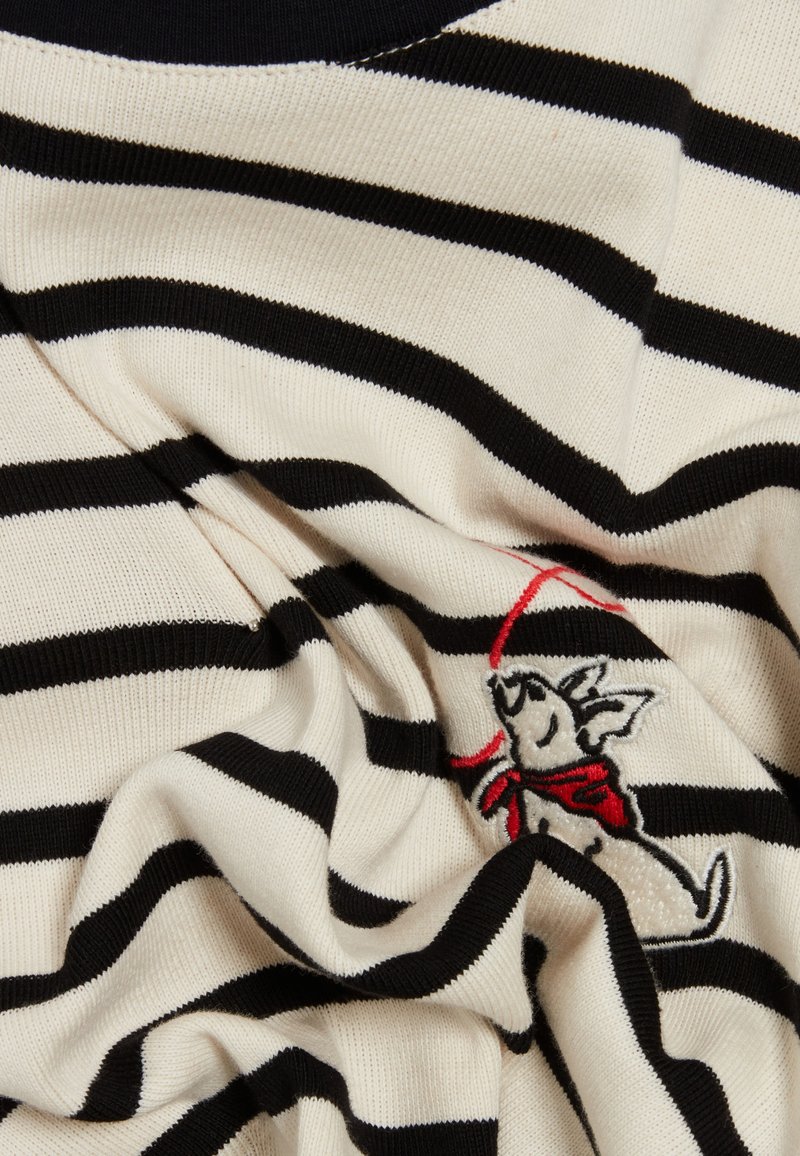 Sweter w paski w odcieniach kremowym i czarnym, z fakturowanym splotem. Ciekawy detal: haftowany królik w czerwonym szaliku na przodzie.