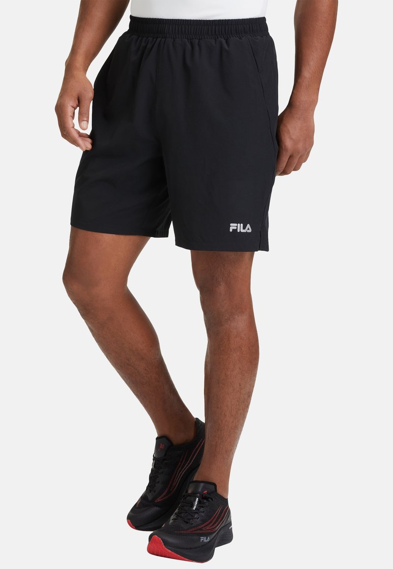 Pantalones cortos deportivos negros con cinturilla elástica y bolsillos laterales. Presenta un logo blanco de FILA en el lado izquierdo. El material parece liviano.
