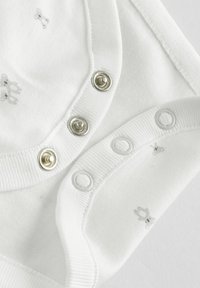 Hvid bomuldsbodies med sølv- og hvide trykknapper, præget af lette kaninmønstre i stoffet. Glat tekstur, afrundede kanter.