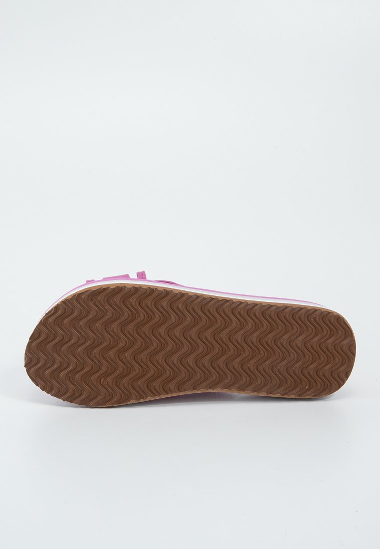 Podeszwa różowego buta z teksturowanym, falistym wzorem; brązowy materiał gumowy; płaski, okrągły kształt; wzmocnione krawędzie wzdłuż boków.