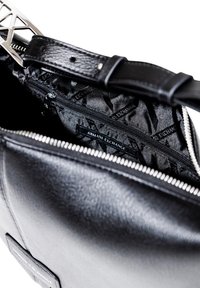 Bolso de mano de cuero negro con cierre de cremallera, superficie texturizada y un interior forrado con el logo y patrón de Armani Exchange.
