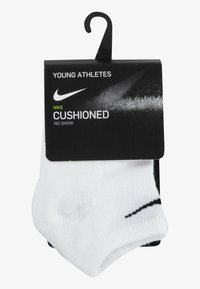 Bijele nevidljive čarape s crnim naglascima, označene kao "ODEBLJANE" za mlade sportaše, na crnoj kartici s kukom za izlaganje.