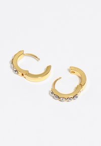 Pendientes de aro de oro con un acabado suave, que presentan cinco cristales transparentes incrustados a lo largo de un borde. Forma circular, diseño con bisagra.