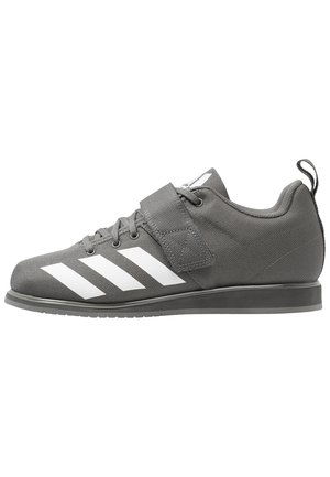 Chaussure de sport grise avec des rayures blanches, des lacets et une large sangle velcro sur le dessus, avec une languette au talon.