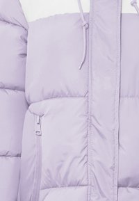 Svetlo vijoličasta napihnjena jakna z zadrgo in žepom, rebrasto teksturo, nastavljivo kapuco s šnurovjem ter kontrastnim belim zgornjim delom.