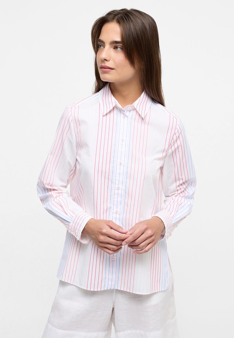 White button-up shirt featuring vertical red and blue stripes, long sleeves, and a classic collar, paired with light-colored pants.