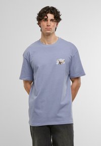 Tricou din bumbac de culoare violet deschis, cu guler rotund și mânecă scurtă, având un design grafic în zona stângă a pieptului. Croială casual.