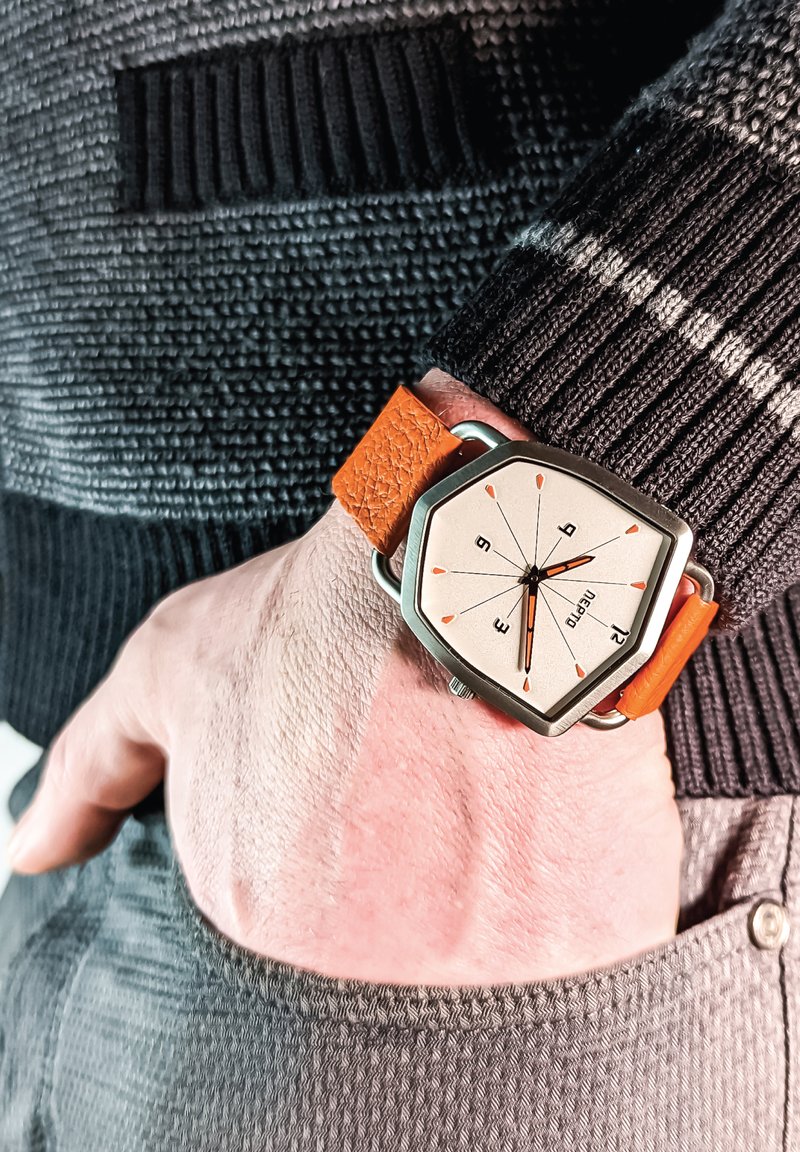 Orange læderrem ur med et hexagonalt sølvur-kabinet og en lys beige urskive. Sorte time markører og orange accent-hænder.