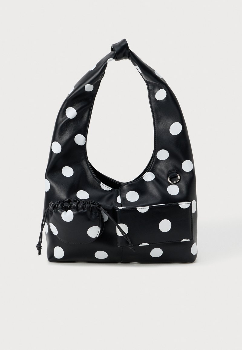 Zwarte synthetische leren tas met witte stippen, voorzien van een geknoopte handgreep, een trekkoordzak en een platte voorkant.