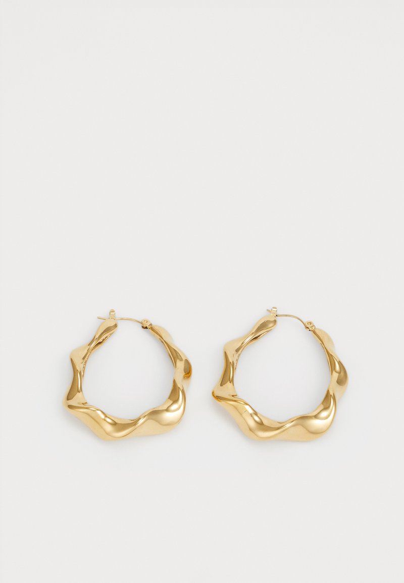 Boucles d'oreilles en or en forme d'anneau avec un design texturé et ondulé. Présentent une fermeture en fil fin et une surface polie et réfléchissante.