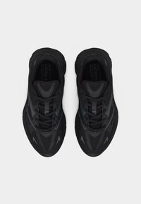 Ζευγάρι μαύρα παπούτσια τρεξίματος Lacoste με πλέγμα και συνθετικό πάνω μέρος, σχέδιο με κορδόνια, εμφανιζόμενα από πάνω σε λευκό φόντο.