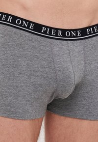 Graue Boxer-Briefs aus weichem Stoff, mit einem schwarzen Bund, auf dem "PIER ONE" in weißer Schrift steht. Glatte Textur mit passgenauer Gestaltung.